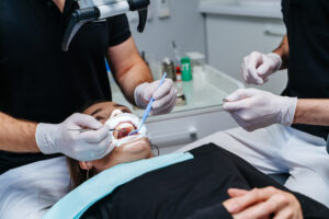 Male dentist treating patient teeth at modern dental clinic office